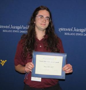 a photo of Tyler Blizzard posing with the 'Service Above Self' award